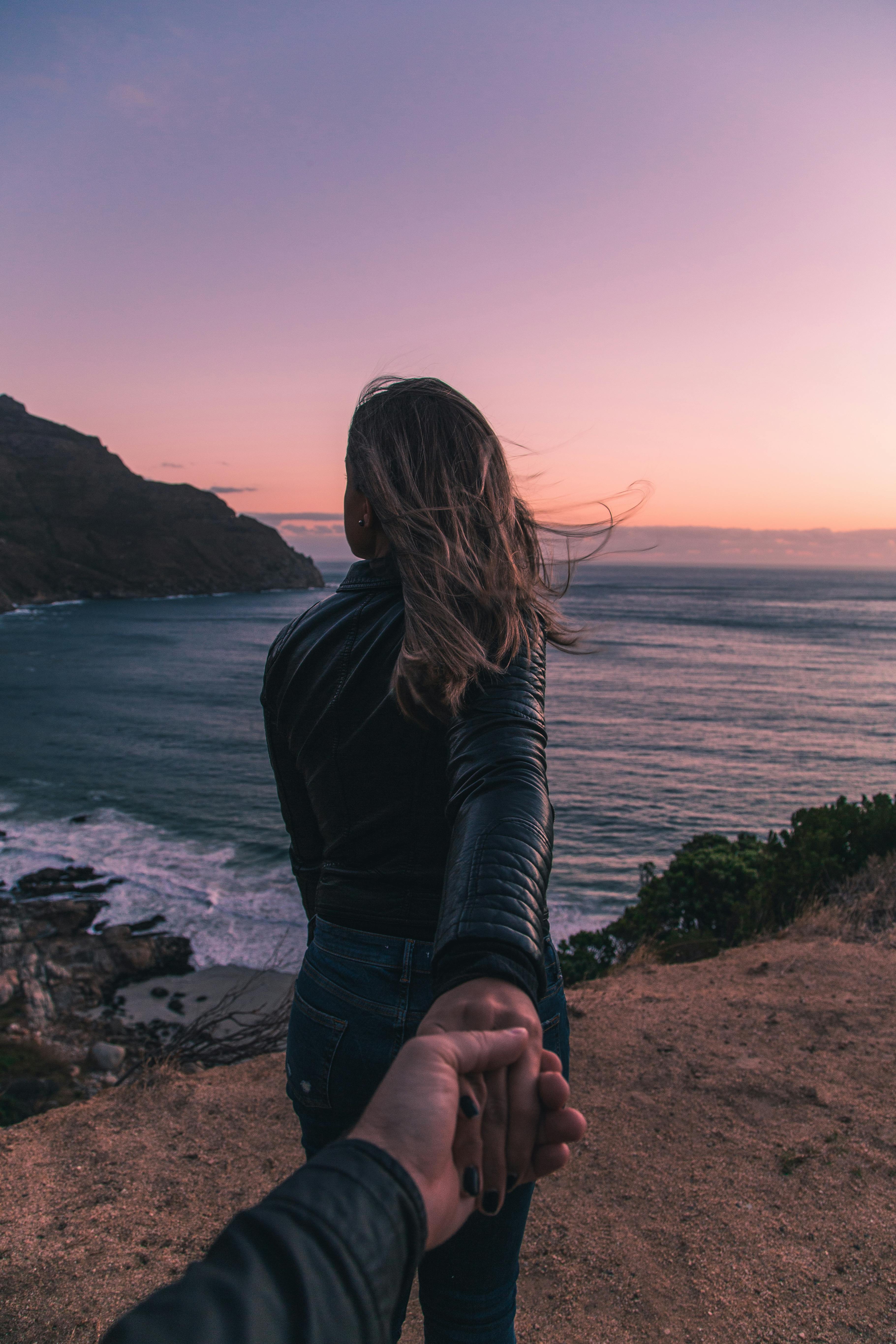 Couple holding hands overlooking a city at dusk