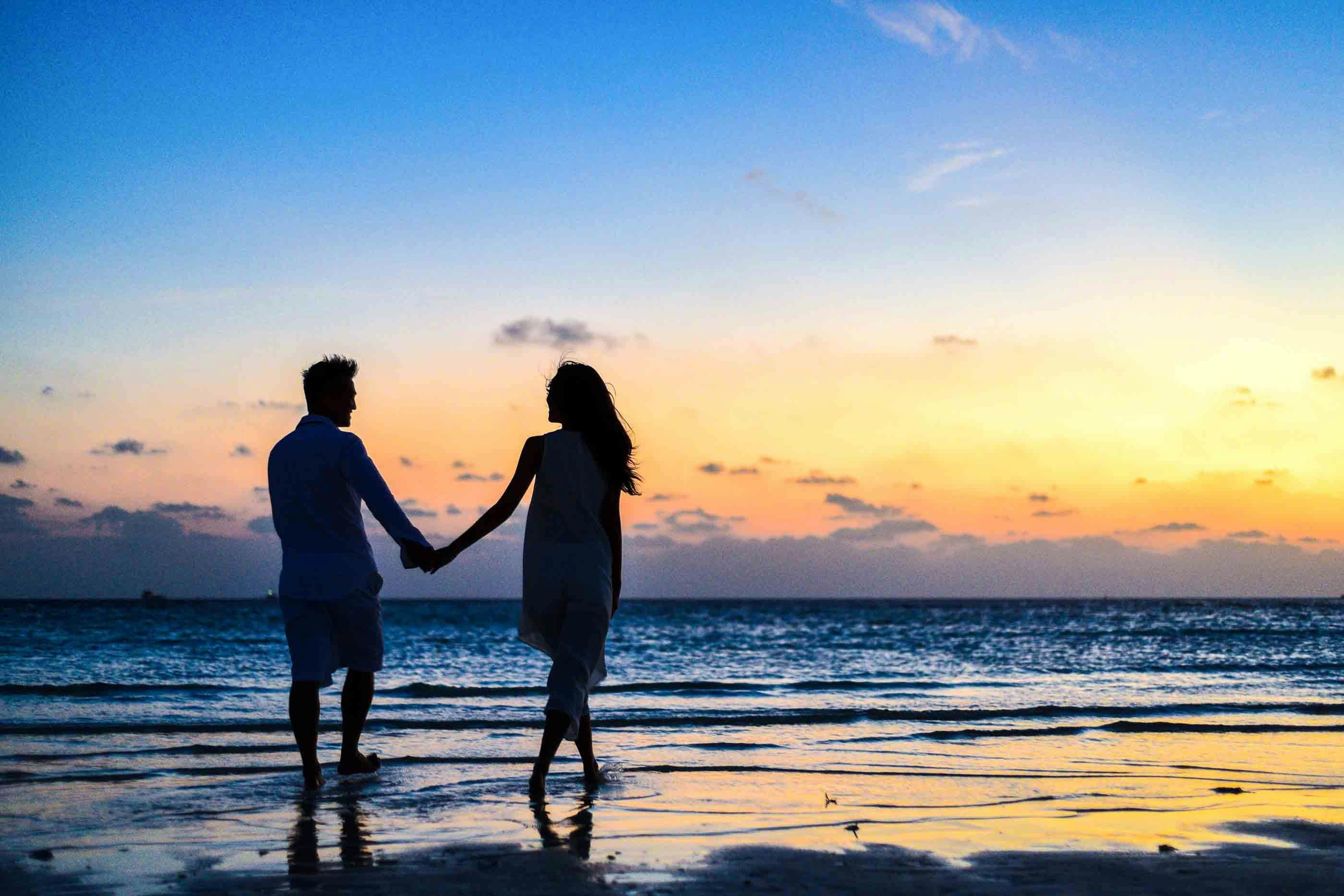 Couple walking together on the beach at sunset
